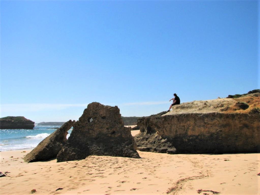 człowiek siedzący na skale na plaży w zatoce Bay of Martyrs Great Ocean Road Australia