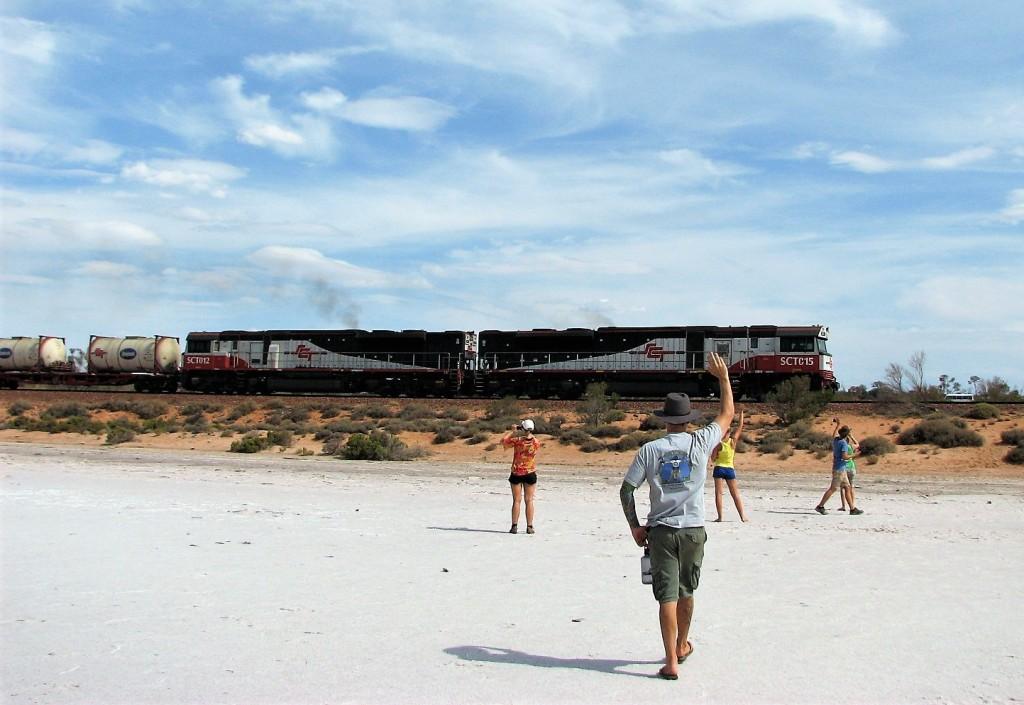 pociąg przejeżdżający przez pustynię machający ludzie