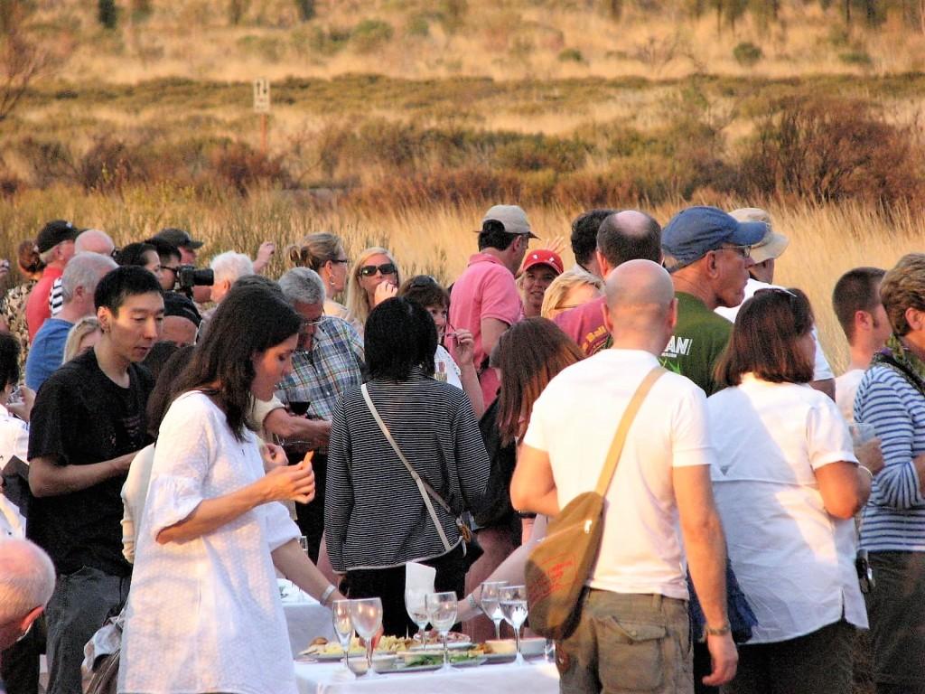 tłumy podziwiające Uluru i stolik z szampanem