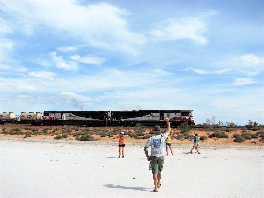 Ludzie machający do przejeżdżającego pociągu stojąc na wyschniętym dnie jeziora Hart Australia